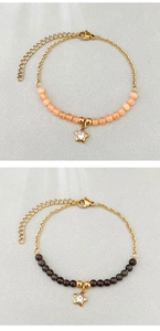Dettaglio di ciondoli a stella su bracciali di perline in acciaio dorato con gancio