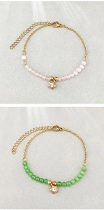 Dettaglio di braccialetti con perline e stella, pietre rosa e verdi e catena d'oro