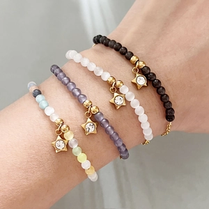 Set di bracciali di perline con ciondoli a stella dorata sul polso di una donna