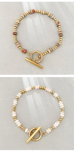 Dettaglio di bracciali boho fatti a mano in pietra con chiusura a levetta dorata