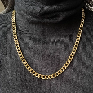 Polished gold stainless steel Cuban chain necklace on a black turtleneck sweater