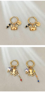 Detailed close-up of golden stainless steel marine earrings with crab and octopus charms