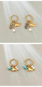 Detail of ocean-themed gold hoop earrings with whale charms, pearls and star stones