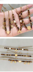Détail du collier de perles en œil de tigre avec breloques dorées en cœur et queue de poisson