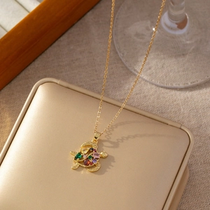 Détail d'un collier pendentif tortue dorée avec des zircons colorés étincelants