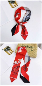 Detail of red floral skinny scarf tied on a straw bag showing summery geometric patterns