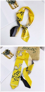 Detail of yellow floral silk scarf tied to straw bag with modern geometric stripe patterns