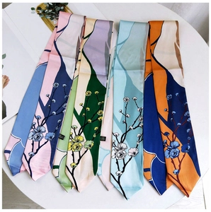 Floral print narrow silk scarves in multiple colors arranged on a white table surface