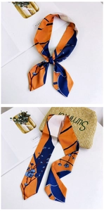 Detailed view of long orange and blue floral twilly silk scarf tied on a summer straw bag