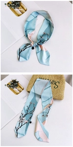Close-up of light blue floral skinny scarf tied on a straw bag for summer style