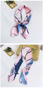 Detail of floral skinny scarf tied as a bow on a straw bag with elegant blossom patterns