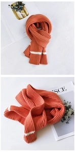 Macro detail of thick orange knit scarf showing soft ribbed texture and white stripes