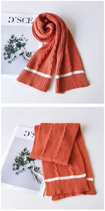 Detail of orange cable knit scarf with white stripe and chunky textured pattern
