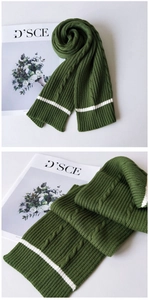 Close-up of dark green cable-knit scarf featuring white stripe detail and soft texture