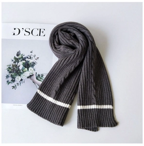 Detail view of dark grey knitted scarf with textured cable knit and white stripe accents