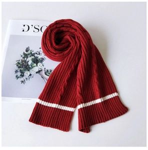 Detail of red cable-knit winter scarf featuring bold white contrast stripes on thick yarn