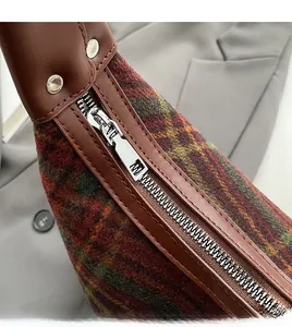 Detailed macro shot of the durable metal zipper on a checkered wool shoulder bag