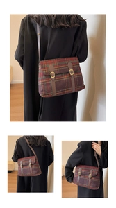 Detail van vintage rood-groene geruite crossbodytas met leren riemen en gouden gespen