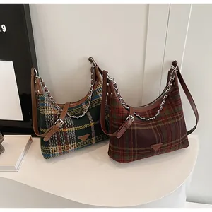 Detail of plaid tweed underarm bags with leather trim and silver chain decorations