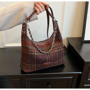 Detail of plaid wool tote bag featuring brown leather handles and silver metal chain