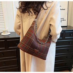 Detail of vintage plaid hobo bag with leather trim and gold chain on a shoulder
