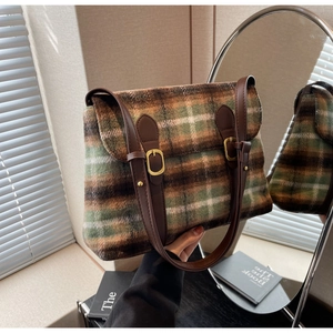 Detail van vintage geruite tweed schoudertas met bruine lederen riemen en gouden gespen