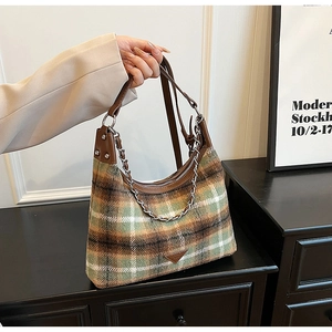 Detail of plaid wool shoulder bag with brown leather strap and silver chain accent