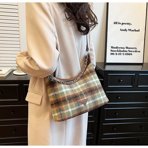 Close-up of retro plaid pattern wool fabric and triangular metal logo on shoulder bag