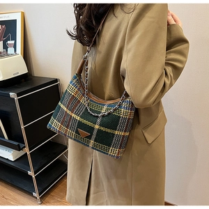 Detail of vintage plaid tweed underarm bag with leather strap and metal chain on model