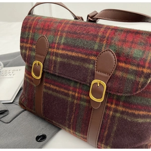 Detail van vintage geruite messenger tas met wollen textuur en bruine lederen gespbanden