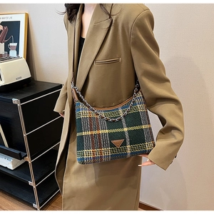 Detail shot of plaid wool fabric texture and silver chain on green vintage shoulder bag