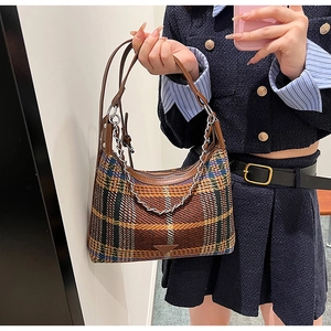 Close-up of vintage plaid tweed shoulder bag with leather trim and metal triangle detail