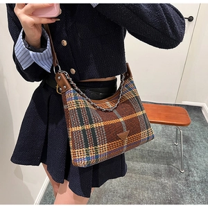 Detail of plaid wool shoulder bag with chain strap and triangular leather patch
