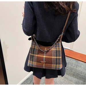 Macro shot of plaid tweed handbag with leather strap and iconic triangular metal logo