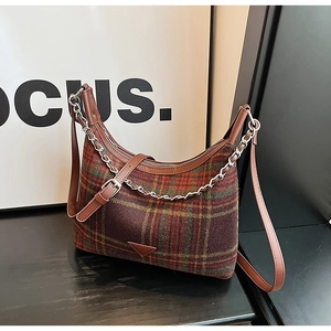 Detail of red-brown plaid crossbody bag with leather trim and silver chain strap