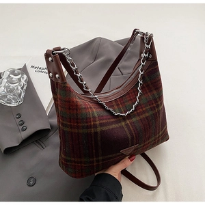 Detail of red and green plaid wool handbag with brown leather trim and metal chain strap