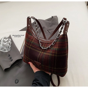 Detail of plaid wool shoulder bag featuring metal chain and adjustable leather strap