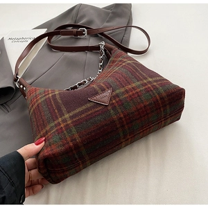 Detailed macro view of vintage plaid wool handbag featuring leather strap and chain