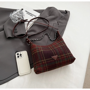 Close-up of retro plaid crossbody bag with leather strap and chain on a stylish blazer