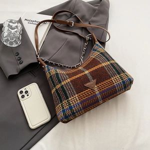 Plaid wool shoulder bag with leather trim and metal chain strap shown in a lifestyle set