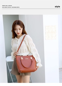 Gros plan d'un sac cabas marron tissé montrant la texture et le logo en métal doré