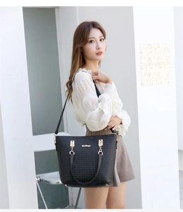Détail d'un sac cabas en cuir tressé noir avec logo doré et bandoulière ajustable