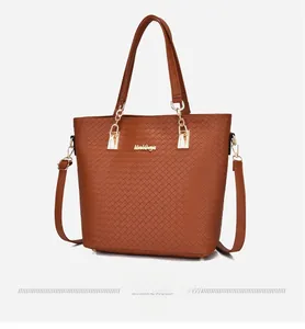 Détail du sac cabas tressé marron avec poignées chaîne dorées et bandoulière