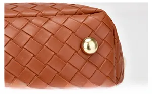 Détail des pieds de protection en métal doré sur le fond en cuir tressé d'un sac