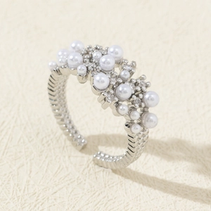 Detail of silver open ring featuring white pearls and shimmering zircon stones inlay