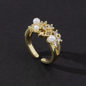 Detail of adjustable gold ring featuring white pearls and shimmering zircon stones
