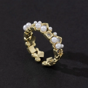 Macro detail of adjustable gold ring with inlaid pearls and cubic zirconia squares