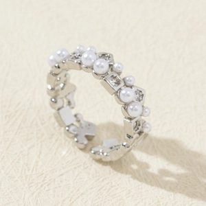 Macro shot of silver ring with white pearls, square zircons and hollow flower patterns