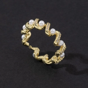 Macro detail of wave-shaped golden pearl ring with sparkling zircon stone settings