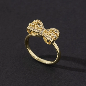 Gros plan sur une bague noeud dorée avec micro-pavés de cristaux et texture tissée